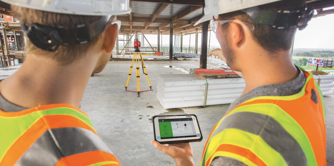 Two workers onsite using a Total Station to position MEP supports